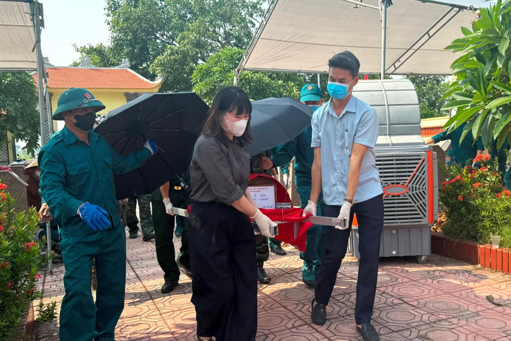 Phó Chủ tịch UBND xã Vân Đình Phạm Thúy Hoà cùng các lực lượng trang trọng đưa hài cốt liệt sĩ về khu vực lấy mẫu sinh phẩm. Ảnh: Mai Hoa